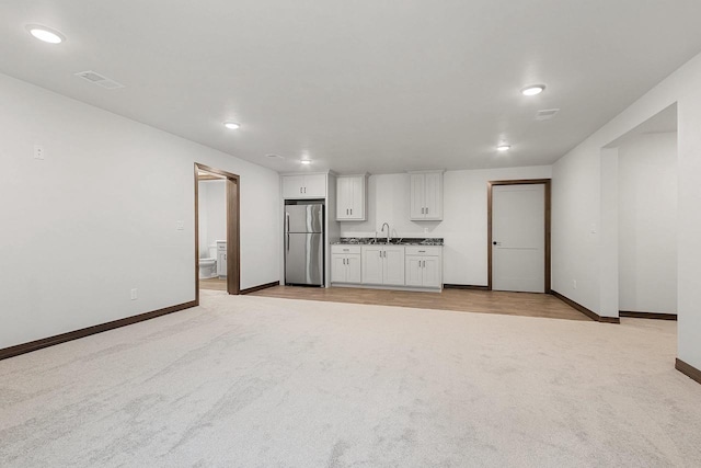 unfurnished living room with light colored carpet and sink