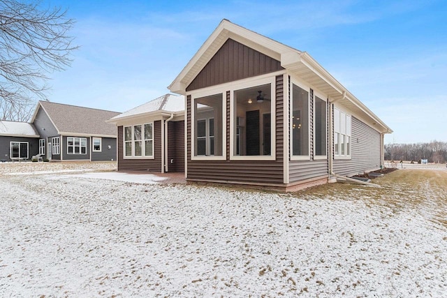 snow covered rear of property with a sunroom