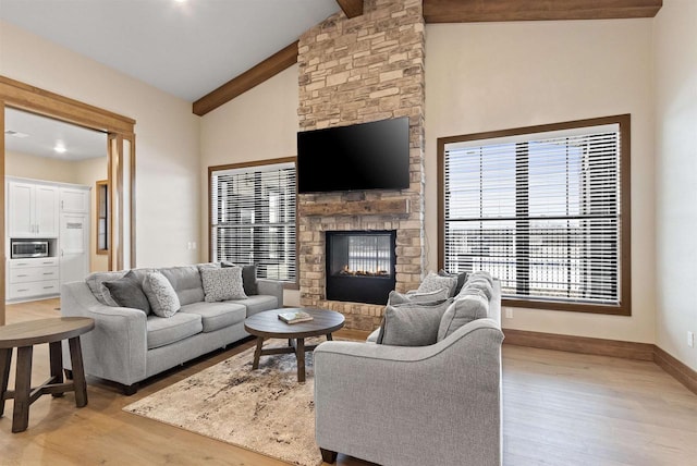 living room featuring a fireplace, lofted ceiling with beams, and light hardwood / wood-style flooring