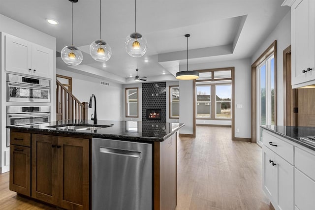 kitchen with white cabinetry, hanging light fixtures, and a tray ceiling