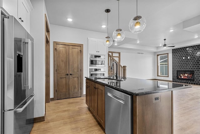 kitchen featuring white cabinetry, an island with sink, decorative light fixtures, and appliances with stainless steel finishes