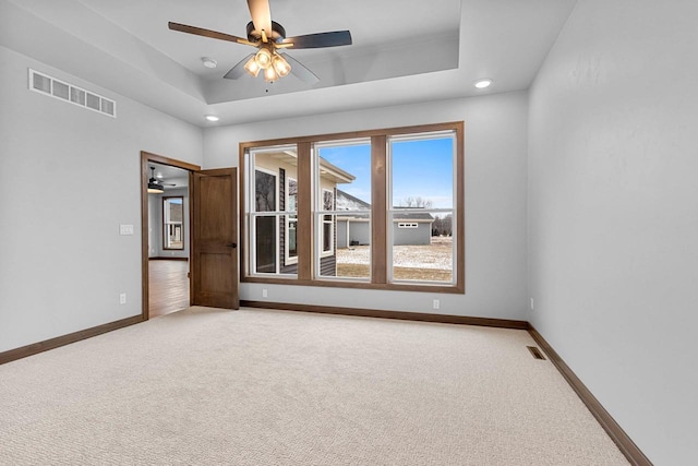 carpeted empty room featuring a tray ceiling and ceiling fan