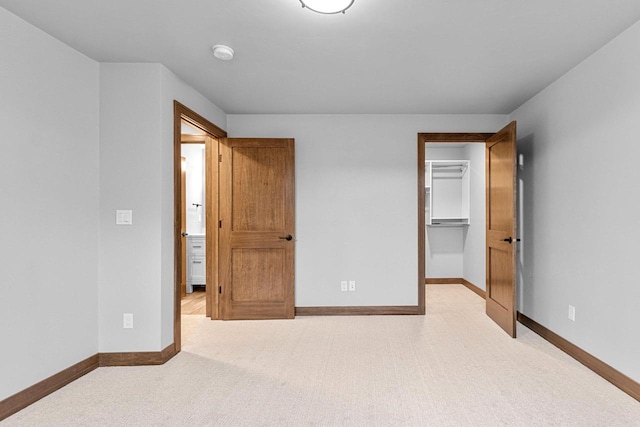 unfurnished bedroom with light colored carpet and a spacious closet