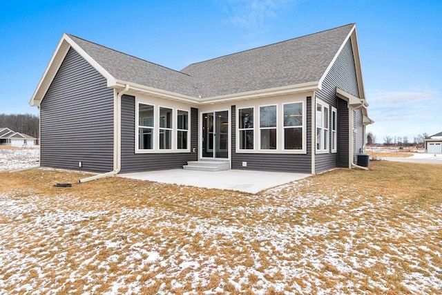 snow covered rear of property featuring a patio area and central air condition unit