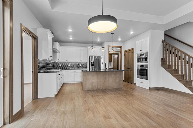 kitchen featuring a center island with sink, white cabinets, sink, hanging light fixtures, and appliances with stainless steel finishes