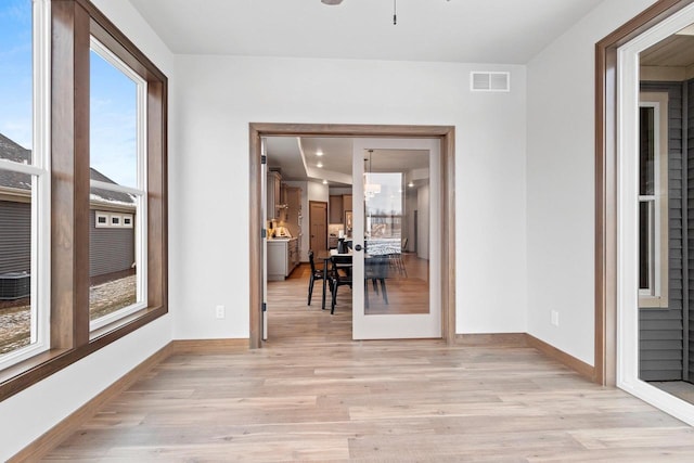 unfurnished sunroom featuring ceiling fan with notable chandelier, a healthy amount of sunlight, and french doors