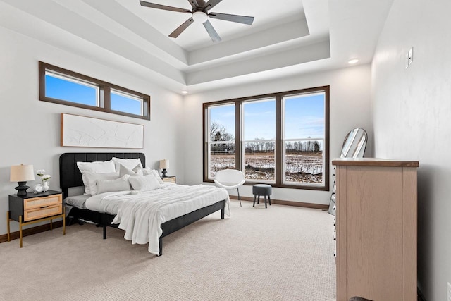 carpeted bedroom featuring a tray ceiling, multiple windows, and ceiling fan