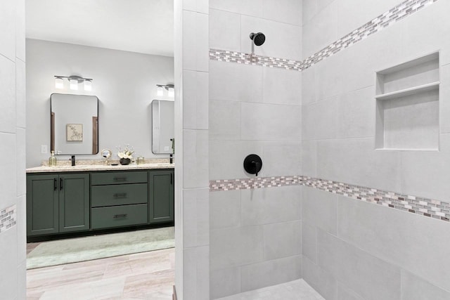 bathroom featuring tiled shower and vanity