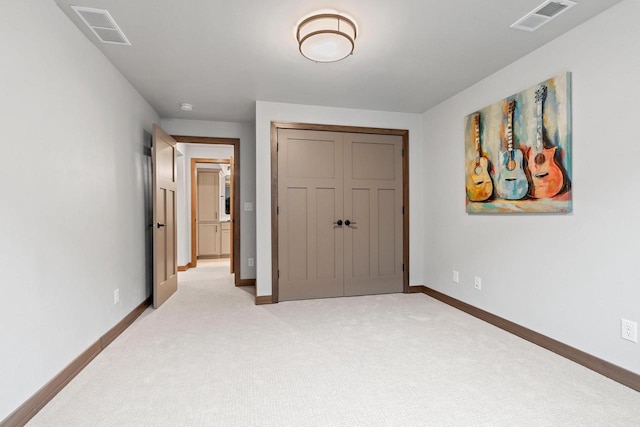 unfurnished bedroom with a closet and light colored carpet