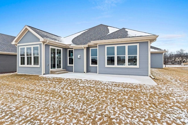 snow covered back of property with a patio