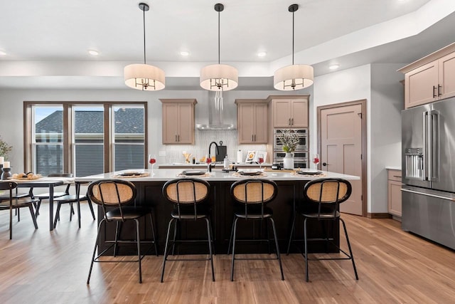 kitchen featuring decorative light fixtures, stainless steel appliances, a kitchen island with sink, and tasteful backsplash