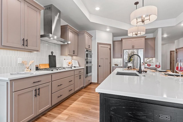 kitchen featuring backsplash, sink, wall chimney exhaust hood, and decorative light fixtures