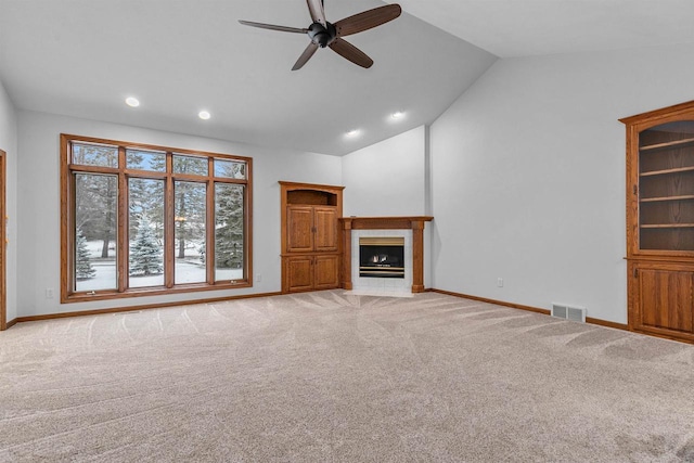 unfurnished living room with light carpet, vaulted ceiling, ceiling fan, and a tiled fireplace