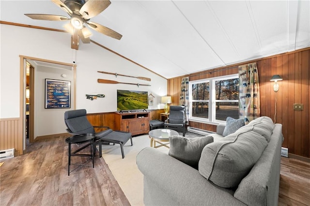 living room with ceiling fan, a baseboard radiator, and wood walls