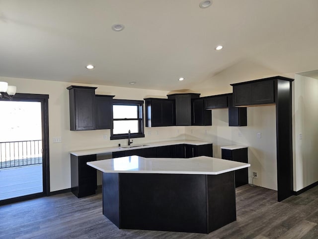 kitchen featuring dark hardwood / wood-style flooring, a center island, lofted ceiling, and sink