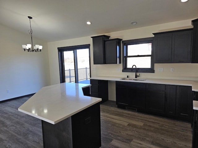 kitchen featuring sink, decorative light fixtures, an inviting chandelier, dark hardwood / wood-style floors, and a kitchen island