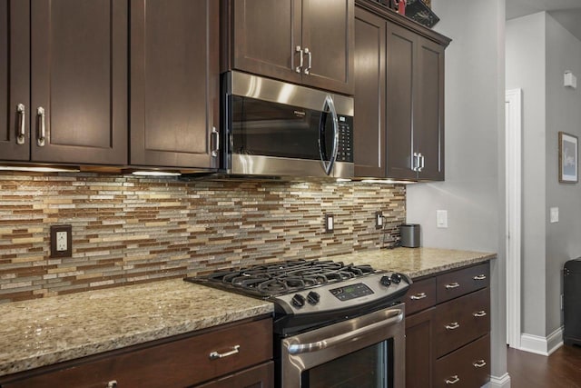 kitchen with dark brown cabinetry, stainless steel appliances, light stone counters, and tasteful backsplash