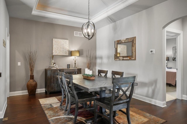 dining space with a chandelier, ornamental molding, dark wood-type flooring, and a tray ceiling