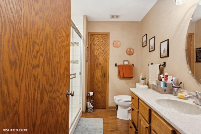 bathroom with vanity, toilet, wood-type flooring, and an enclosed shower