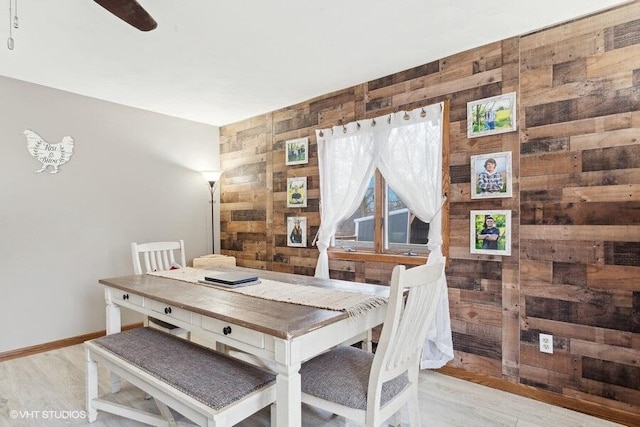 dining space with ceiling fan and wooden walls