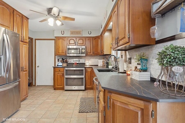 kitchen with appliances with stainless steel finishes, sink, backsplash, ceiling fan, and light tile patterned floors