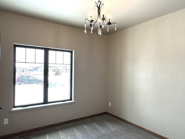 carpeted empty room with an inviting chandelier