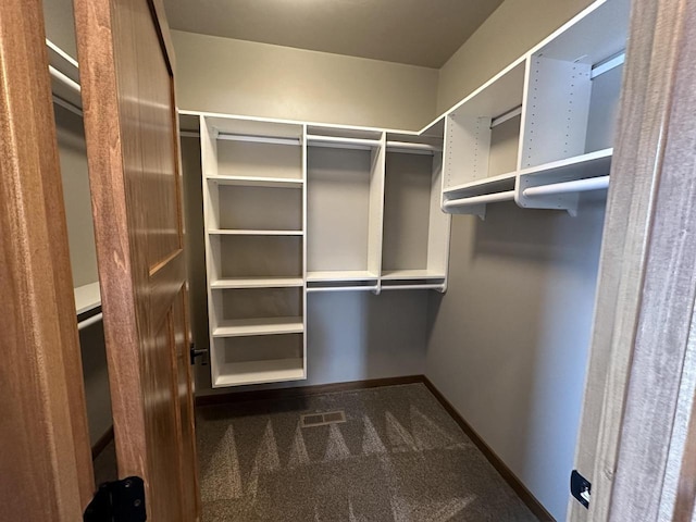 walk in closet with dark carpet