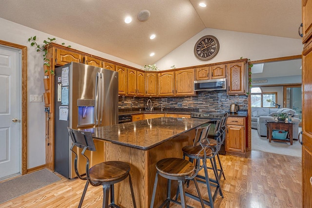 kitchen with a center island, sink, light wood-type flooring, tasteful backsplash, and stainless steel appliances