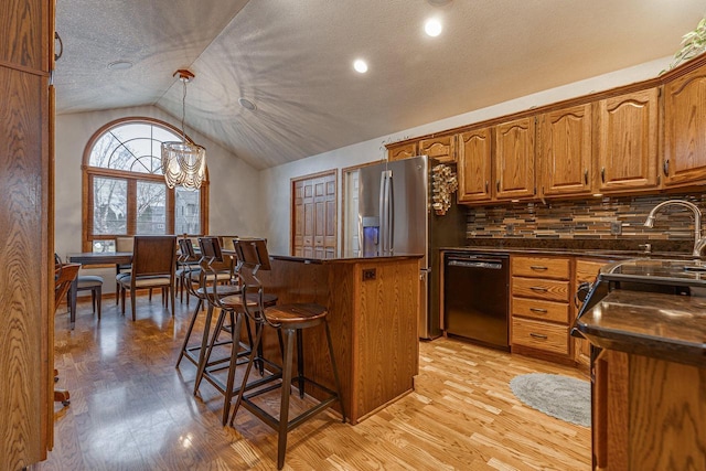 kitchen featuring dishwasher, sink, decorative light fixtures, lofted ceiling, and decorative backsplash