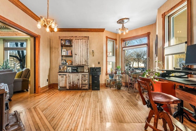 home office featuring a notable chandelier, light hardwood / wood-style flooring, and ornamental molding