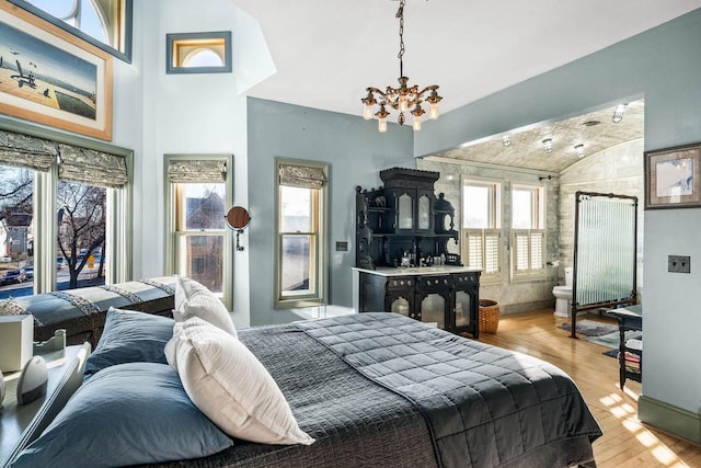 bedroom featuring lofted ceiling, light wood-type flooring, and a chandelier