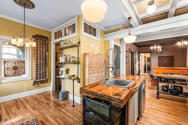 kitchen featuring light hardwood / wood-style flooring, decorative light fixtures, a kitchen island with sink, ornamental molding, and sink