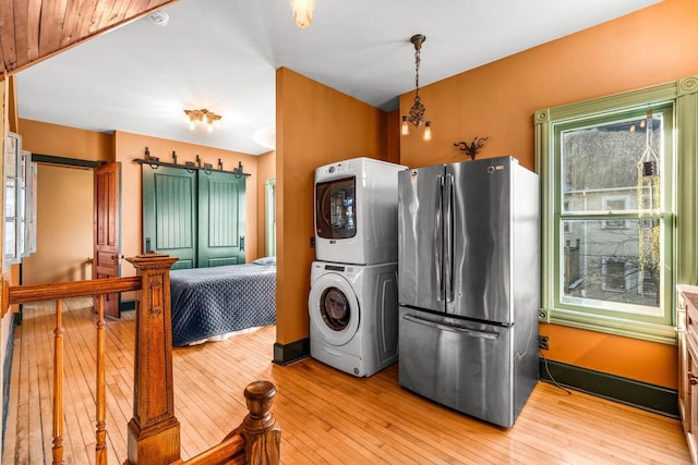 washroom with stacked washer and dryer and light hardwood / wood-style floors