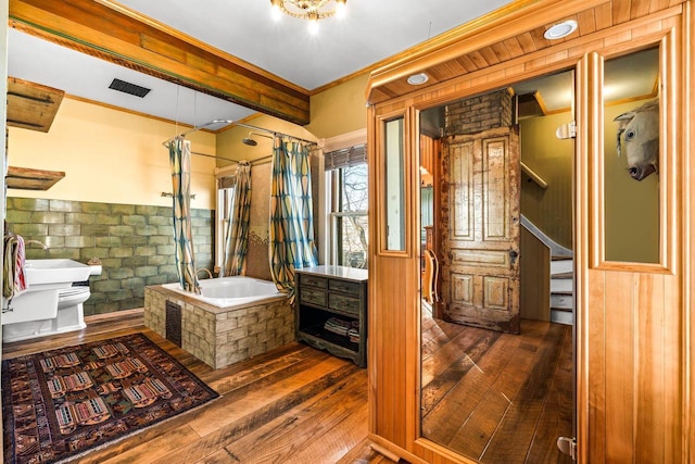 bathroom with toilet, wood walls, hardwood / wood-style floors, crown molding, and shower / bath combo