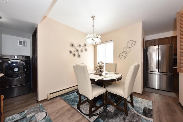 dining area with hardwood / wood-style floors, washer / clothes dryer, baseboard heating, and a notable chandelier