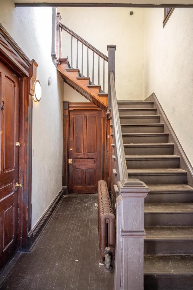 staircase featuring wood-type flooring and radiator heating unit