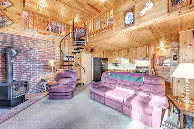 carpeted living room with a wood stove, wooden walls, and wooden ceiling