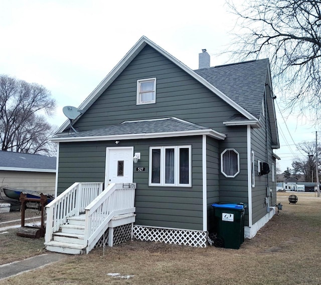 view of front of house featuring roof with shingles and a chimney