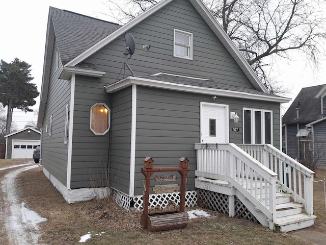 view of front of home featuring a shingled roof, a detached garage, and an outdoor structure