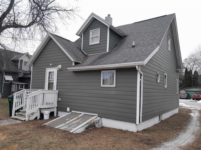 back of house featuring a chimney and a shingled roof