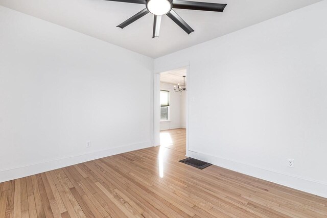 616 Elk St, Sabula, IA 52070 - spare room with ceiling fan with notable chandelier and light wood-type flooring