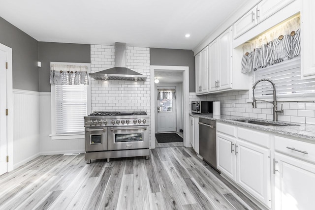 616 Elk St, Sabula, IA 52070 - kitchen featuring sink, wall chimney range hood, stainless steel appliances, white cabinets, and light stone countertops