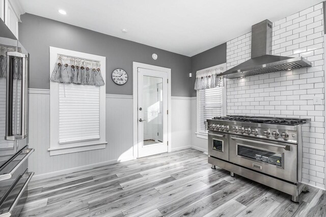 616 Elk St, Sabula, IA 52070 - kitchen featuring light hardwood / wood-style flooring, double oven range, white cabinetry, and wall chimney range hood