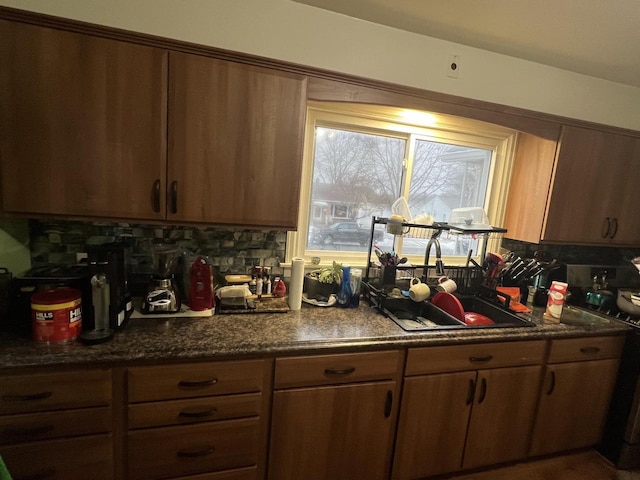 kitchen with tasteful backsplash, range, sink, and dark stone countertops