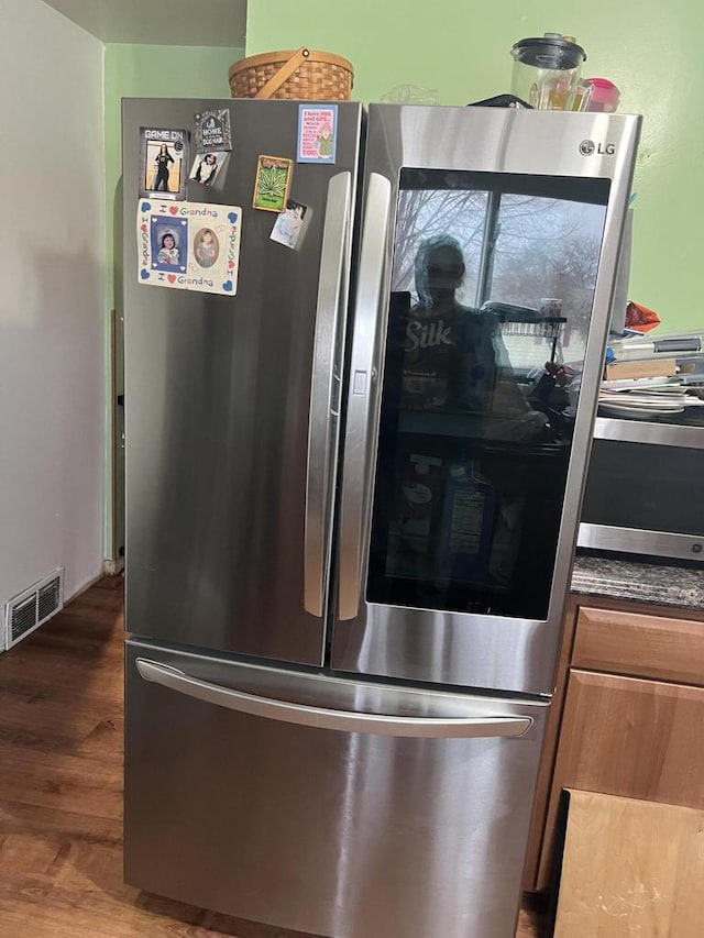 details with dark hardwood / wood-style floors and stainless steel fridge