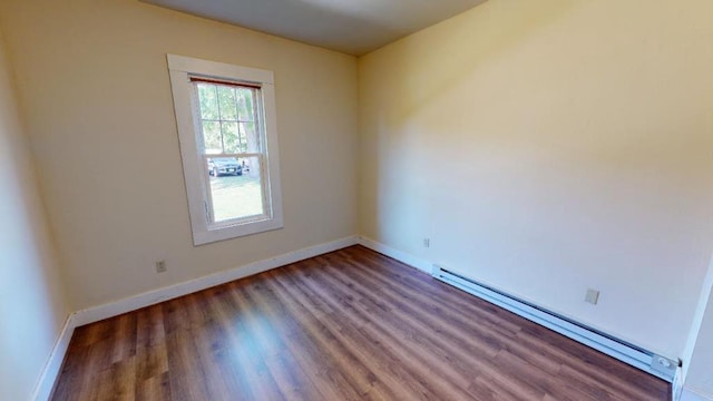 empty room with dark hardwood / wood-style flooring and a baseboard heating unit