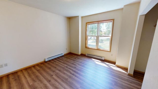 unfurnished room with baseboard heating and hardwood / wood-style floors