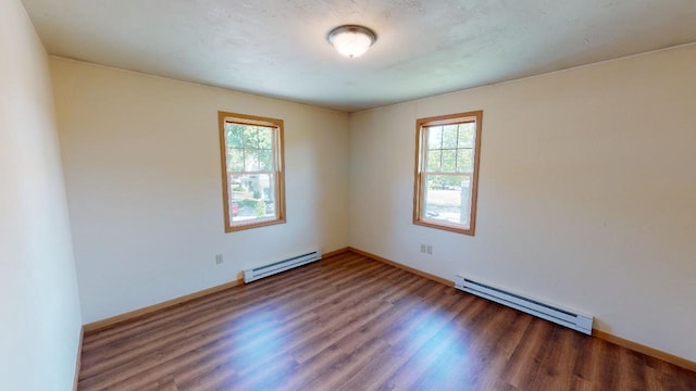 empty room with baseboard heating and dark hardwood / wood-style floors