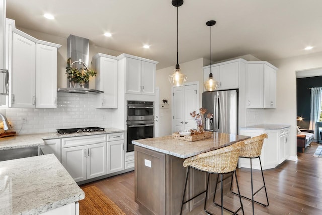 kitchen with white cabinets, wall chimney exhaust hood, a center island, and appliances with stainless steel finishes