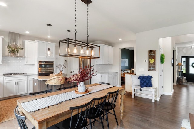 kitchen featuring white cabinets, hanging light fixtures, and wall chimney range hood